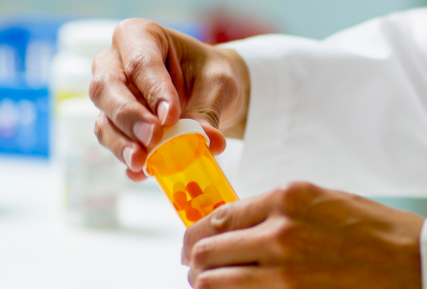 Hands of a pharmacist holding a pill bottle