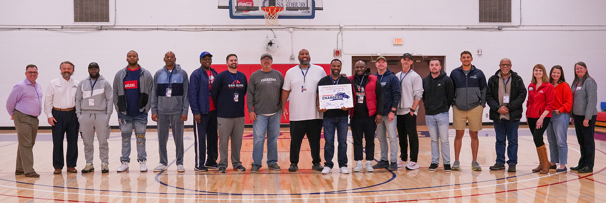 A line of people standing on a basketball court smiling.