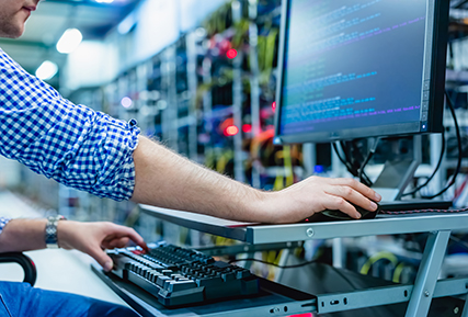 person at a computer terminal in a server room.