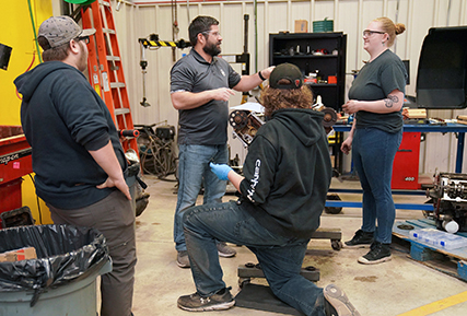 auto instructor talking to students in the auto bay. 