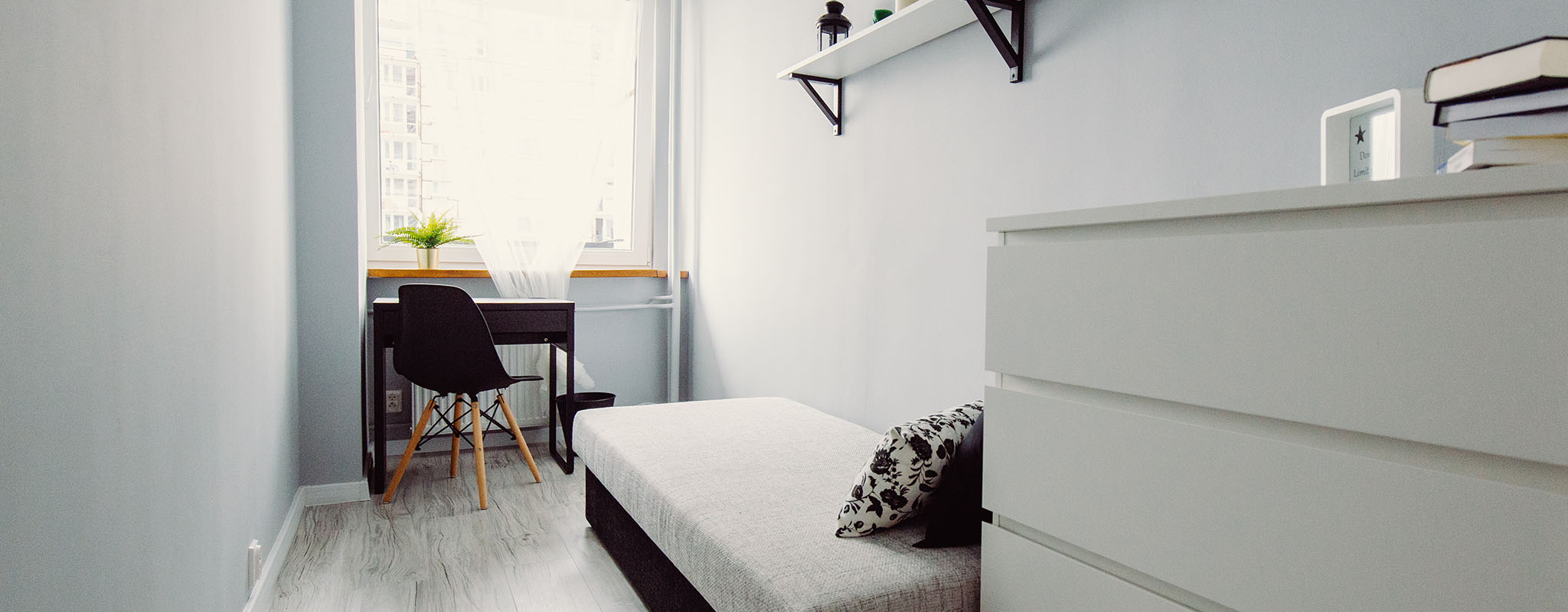 A all white bedroom with a big window letting light in.