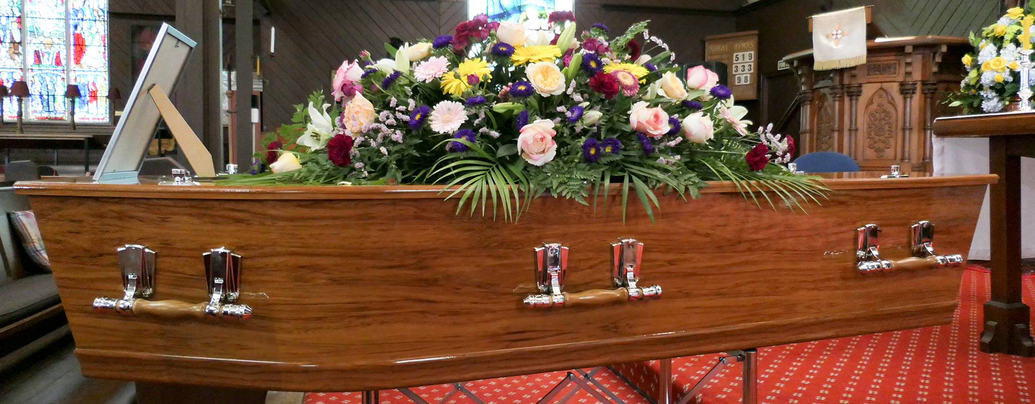 a casket with flowers on top if it in a church.