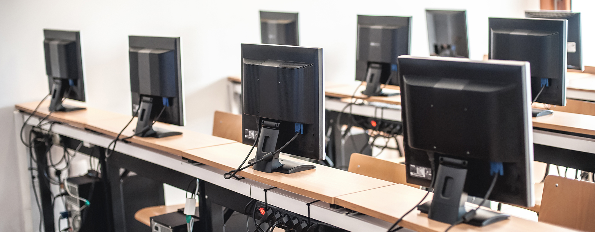 Many computer sitting on a long desk.