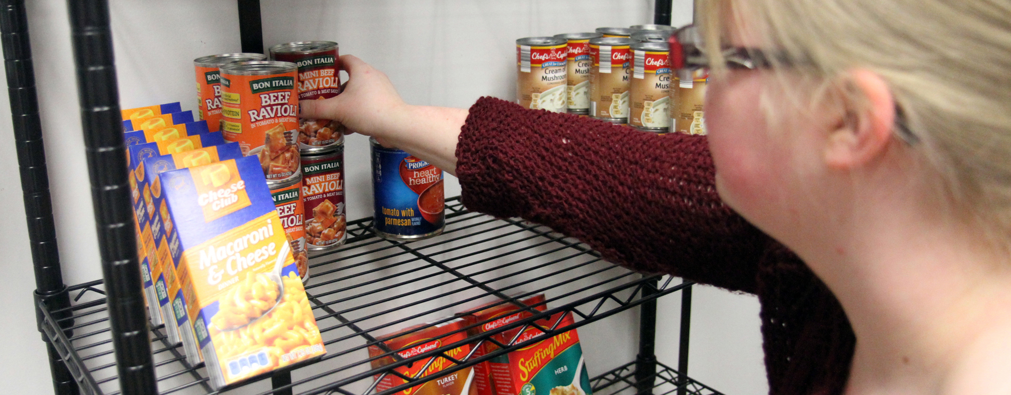 person putting food on shelf.