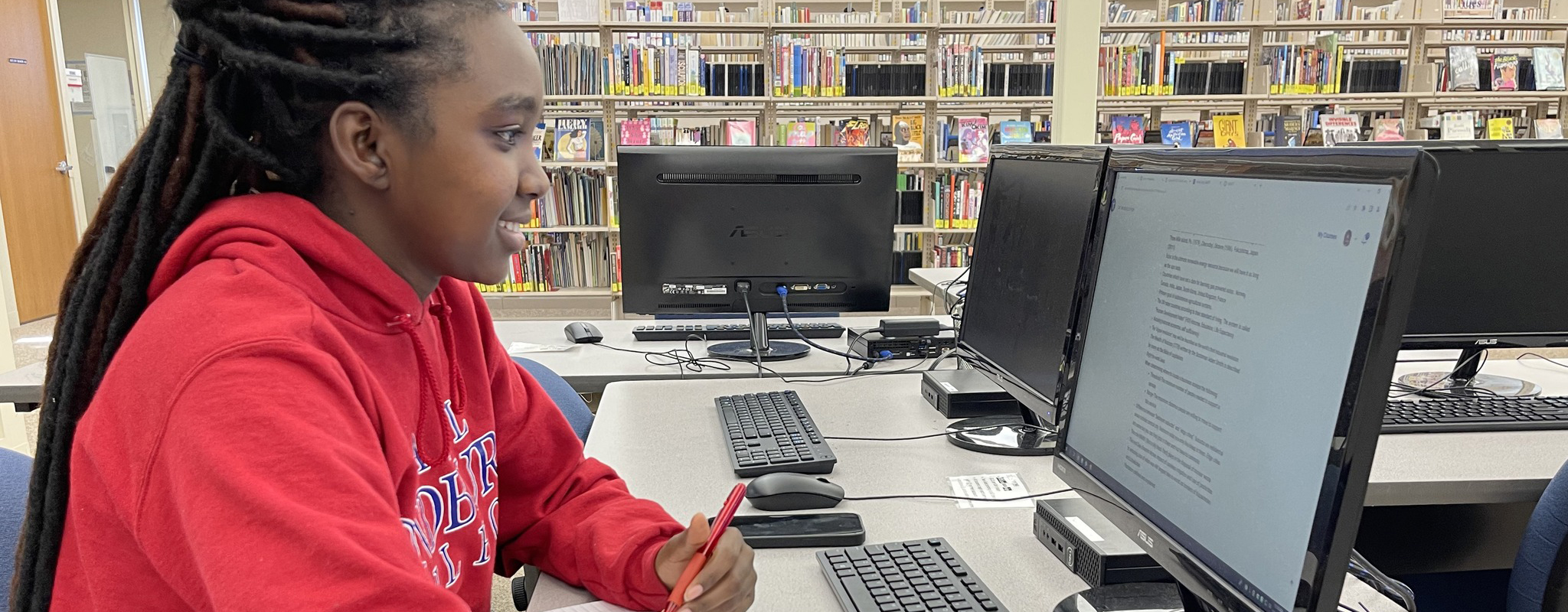 female student in the library looking at a computer monitor.