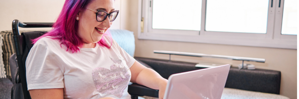 women sitting using a laptop smiling.