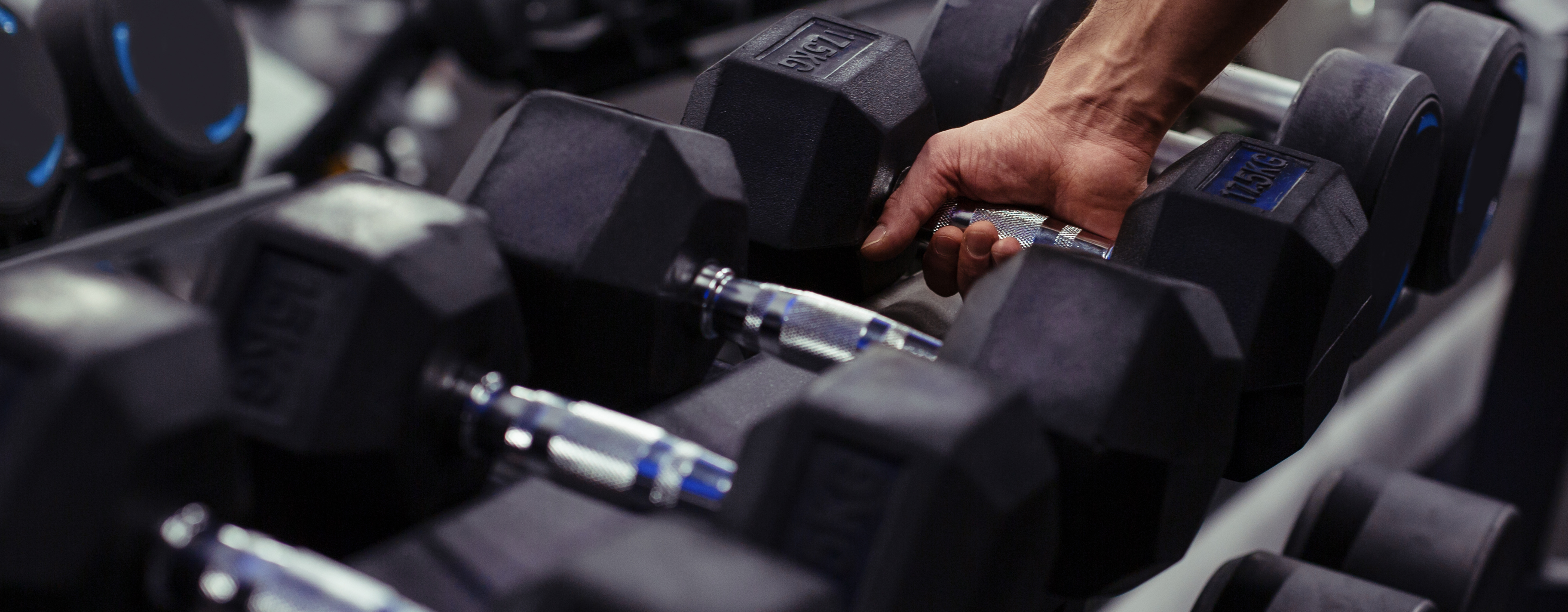 row of dumb bells one is being picked up.